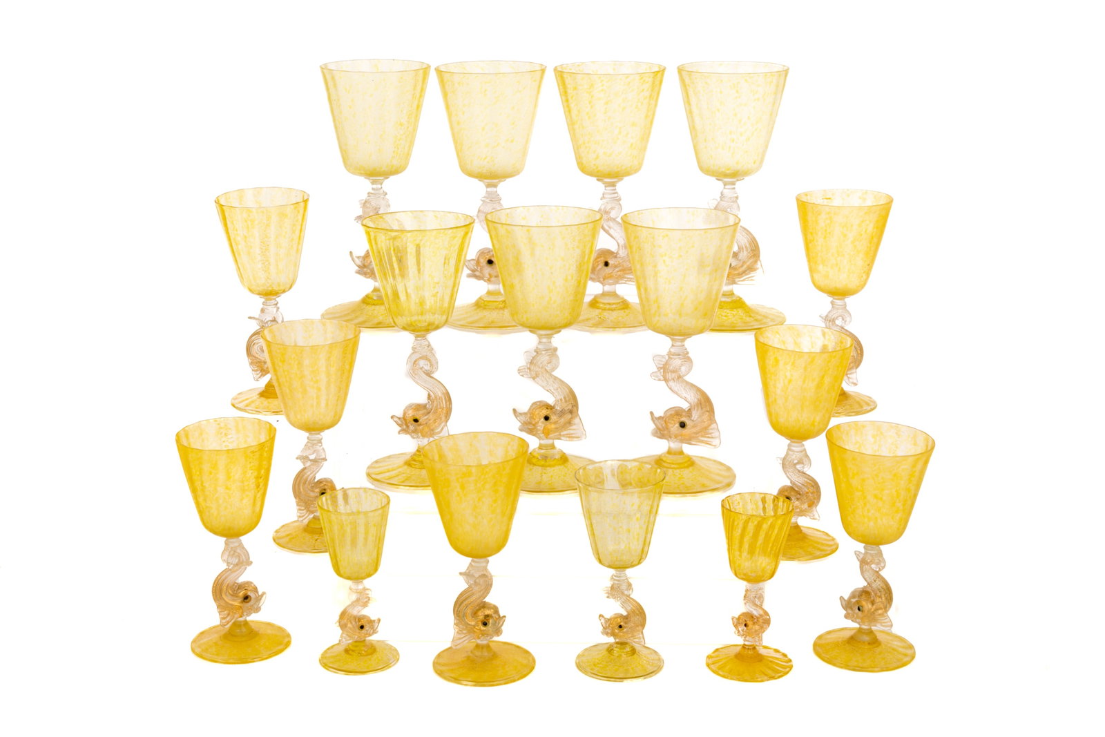 GROUP OF VINTAGE YELLOW MURANO GLASS STEMWARE: Group of seventeen Venetian Murano glasses in a canary yellow glass with gold aventurine inclusions throughout and dolphin stems. Including seven larger water glasses, seven wine glasses,and three sma