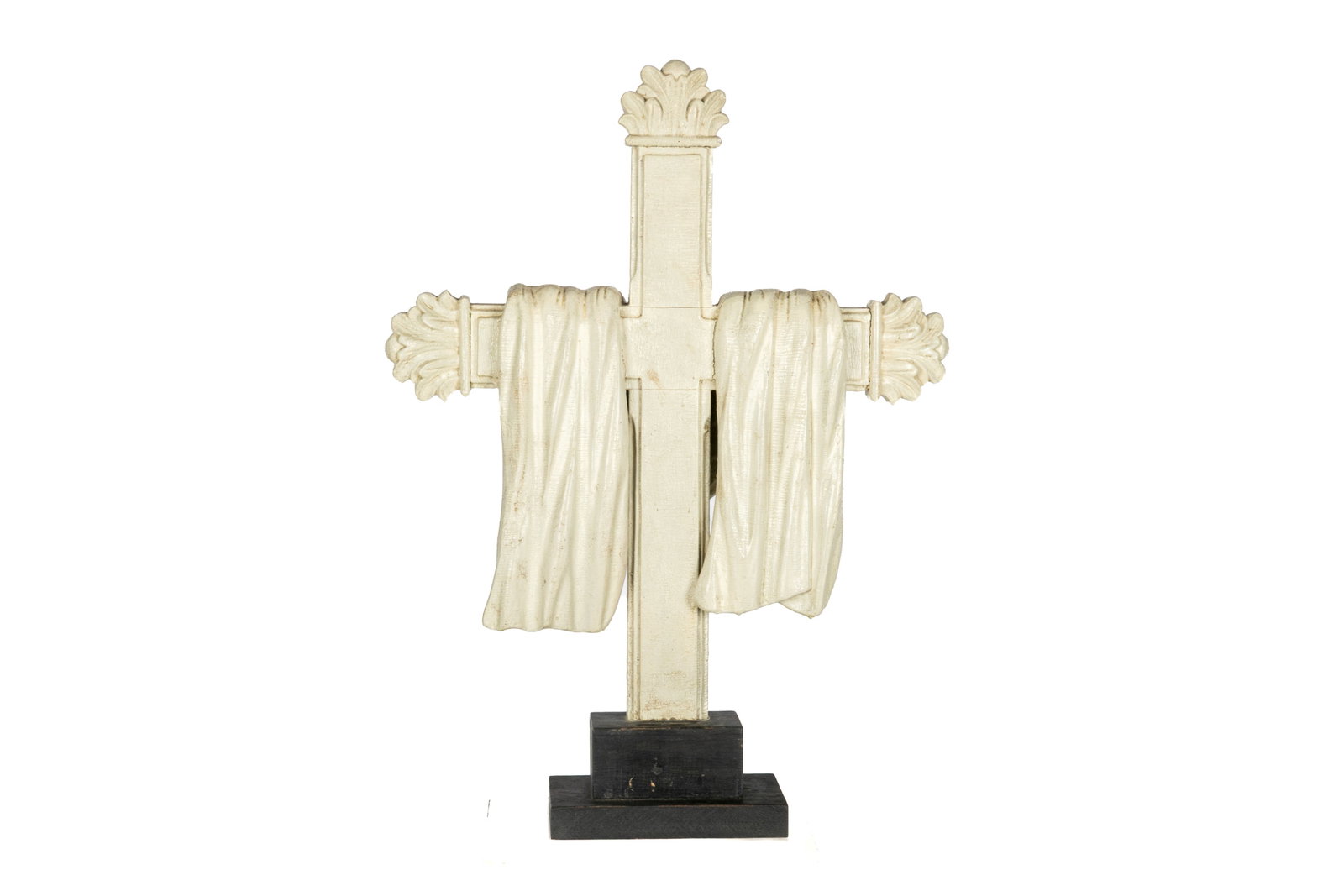 ANTIQUE WHITE PAINTED WOOD CROSS RELIQUE: The architectural fragment with flames on the sides and top of the cross and carved drapery. Measurements (with wooden base): H. 28 1/2" x W. 21 1/4" x D. 6"