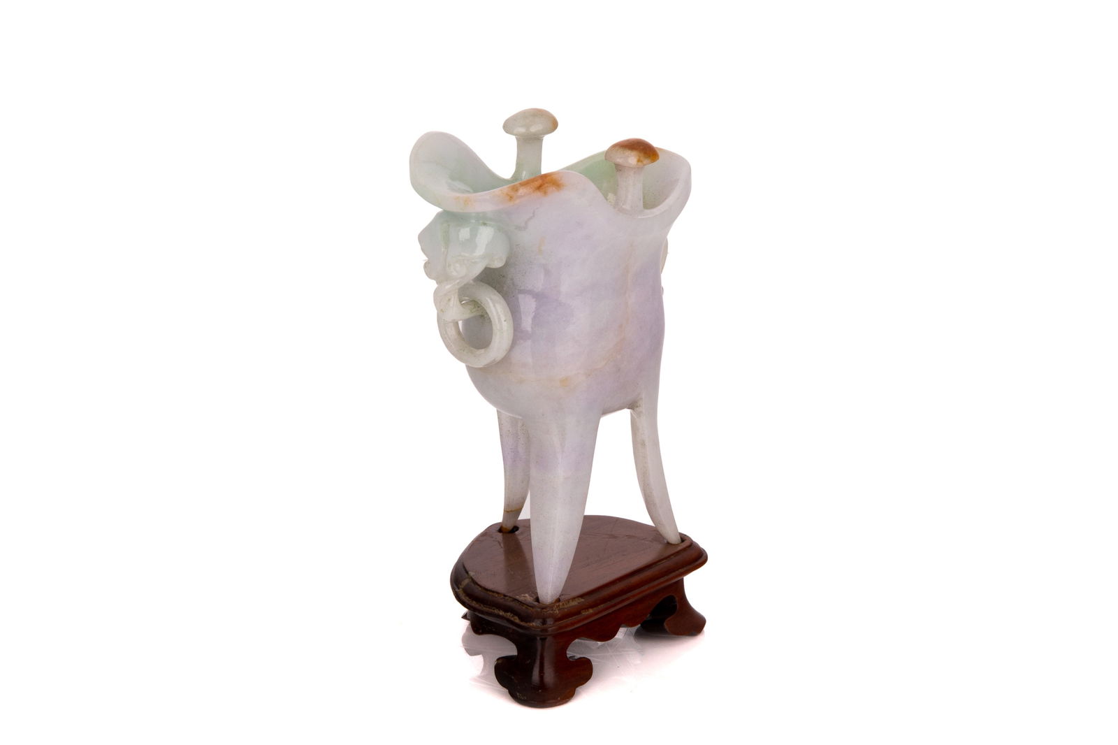LAVENDER JADEITE JUE FORM VESSEL: Raised on three legs, the handle in the form of two lingzhi with a suspended ring. On carved wood stand.H. (with stand) 13.5 cm