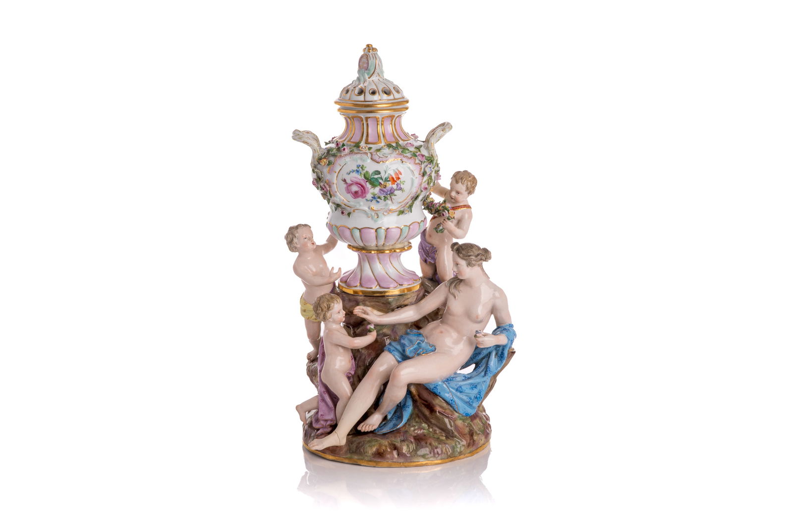 MEISSEN PORCELAIN FIGURAL GROUP: Meissen figural group depicting a nude woman recumbent on a tree stump surrounded by three cherubs. A lidded potpourri urn stands at the centre of the group. Blue crossed swords mark tothe bottom alon