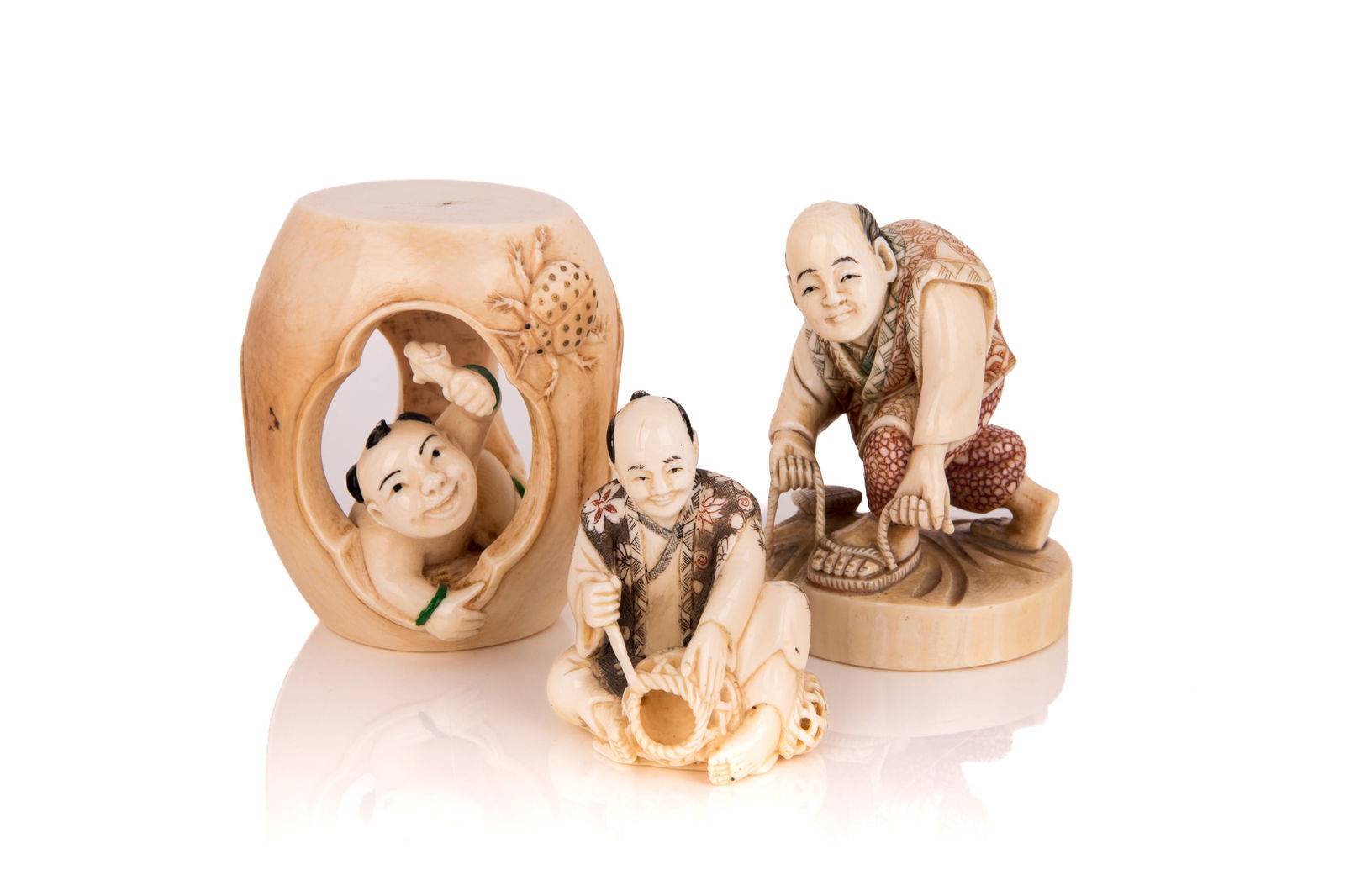 GROUP OF THREE OKIMONO CRAFTSMEN: One tying sandals, another weaving a basket, the third of a young Chinese boy hiding in a barrel and playing with a ladybug. One signed to the base Koshin. H. 6 cm (basket weaver); 7.5 cm (shoe maker)