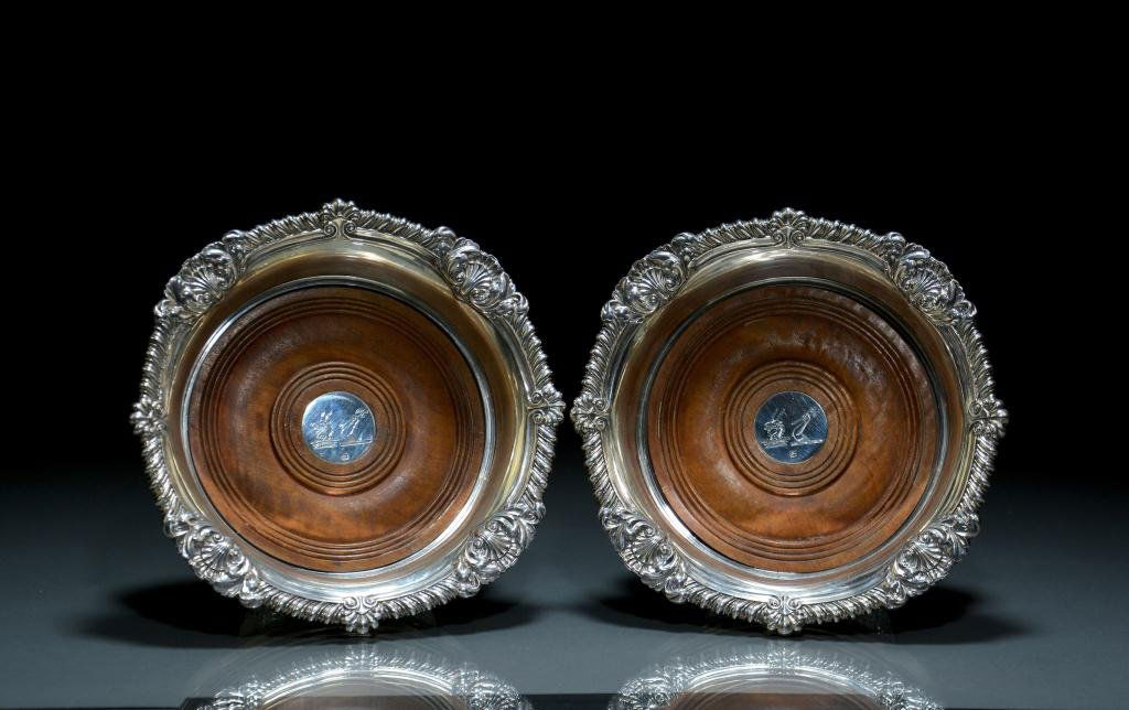 FINE PAIR OF GEORGE III SILVER BOTTLE COASTERS: Gadroon and acanthus leaf border with finely turned wood bases and double crested button. Paul Storr, London, 1816. Dia 18.5 cm. (7 1/4 in.)
