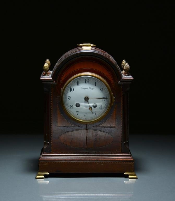 EDWARDIAN MAHOGANY MANTLE CLOCK: With fruitwood inlay and banding, four pinecone finials, enamel dial marked Tempus Fugit. AD Mougin maker's mark. H 29 cm. (11 3/8 in.)