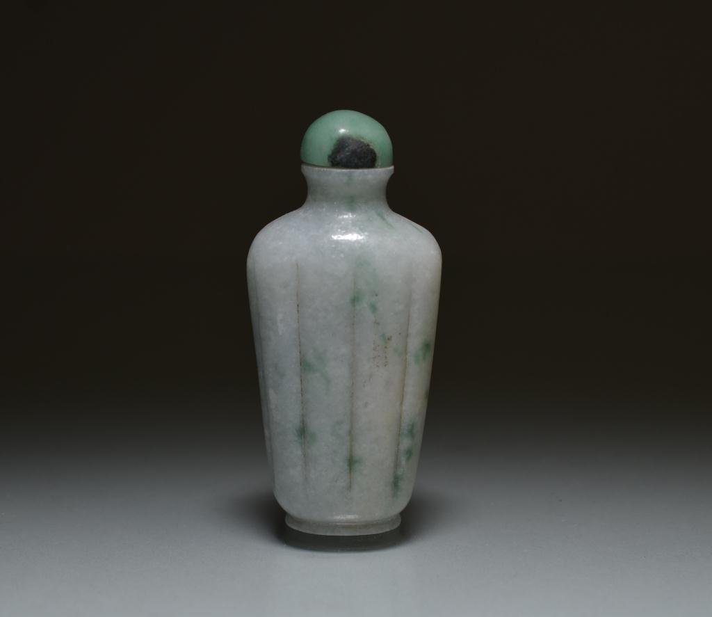 CHINESE CARVED JADEITE SNUFF BOTTLE: White jadeite with minor apple green inclusions; ribbed body, with jadeite stopper. H. 8.5cm (3 3/8 in.)