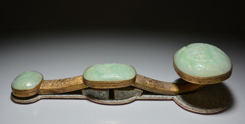 CHINESE JADE AND GILT BRONZE RUYI SCEPTER: Set with three graduating apple-green jade plaques carved with a boy rowing a dragon boat carrying a vase in an open landscape, gilt bronze handle with similar design in two cartouches. With original 