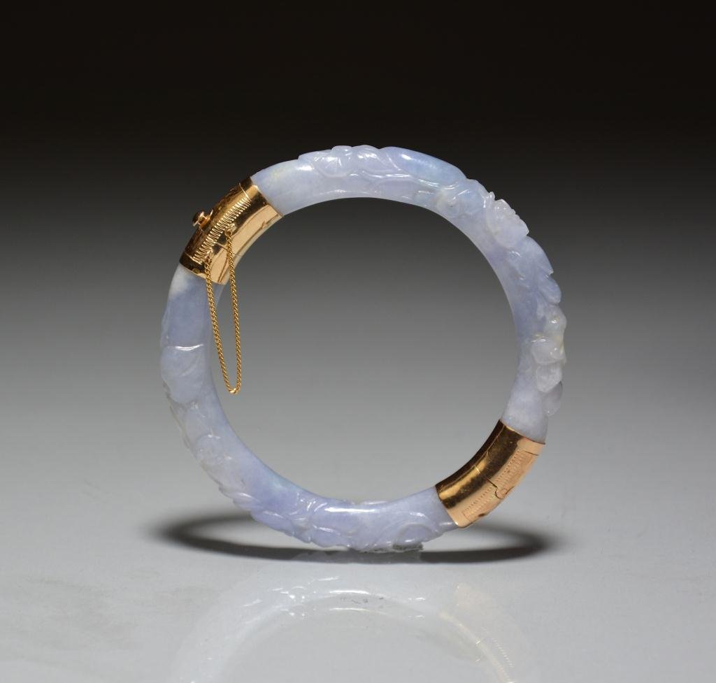 14K YELLOW GOLD AND CARVED LAVENDAR JADE BANGLE: Carved with continuous band of bats and flowers, with engraved 14K yellow gold hinged fitting. Dia. 7.7cm (3 1/8 in.)