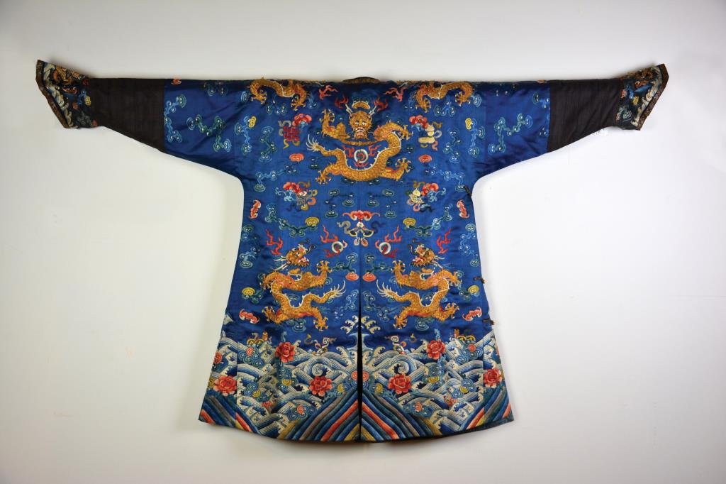 CHINESE EMBROIDERED BLUE IMPERIAL PRINCE ROBE: Embroidered with five-clawed dragons in gold threads and Buddhist emblems, colourful ocean weaves with chrysanthemums at lower section. 19th century. L. 83cm (32 3/4 in.)