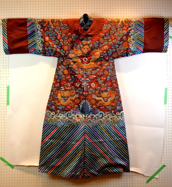 CHINESE EMBROIDERED SILK ROBE: On burgundy ground with five-clawed dragons centering a basket of flower amidst shou symbols and bats, eight precious objects above ocean waves. Guangxu period. L. 148cm (58 1/4 in.)