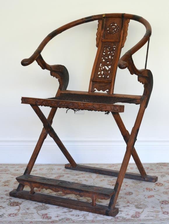 CHINESE HORSESHOE FOLDING CHAIR: Hardwood chair with qilin motif pierced back and rope seat, foot with brass fittings. H 104.5 cm (41 1/8 in.)