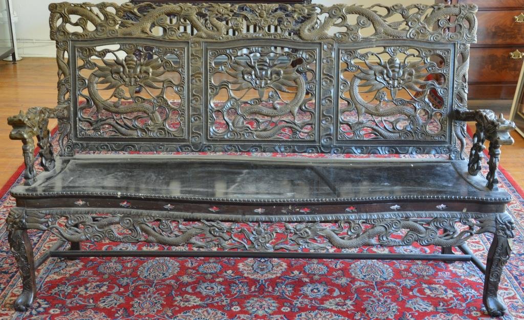 JAPANESE CARVED WOOD SETTEE: Back comprised of three pierced dragon panels surrounded by an ornate border and heavily carved dragon arms. 19th century. L. 184cm (70.5 in.)