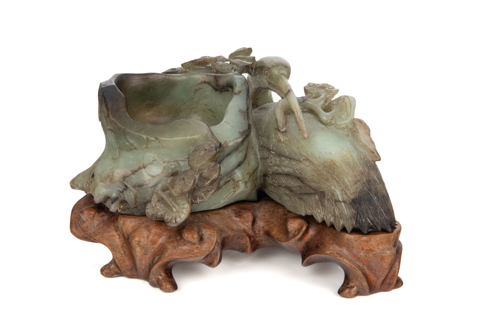 CELADON AND RUSSET JADE EGRET AND BRUSH WASHER: The brush washer of a hollowed pine trunk form, the sides with branches and a reclining egret holding a trifurcated lingzhi in the mouth. On carved hardwood stand. W. 19.5 cm