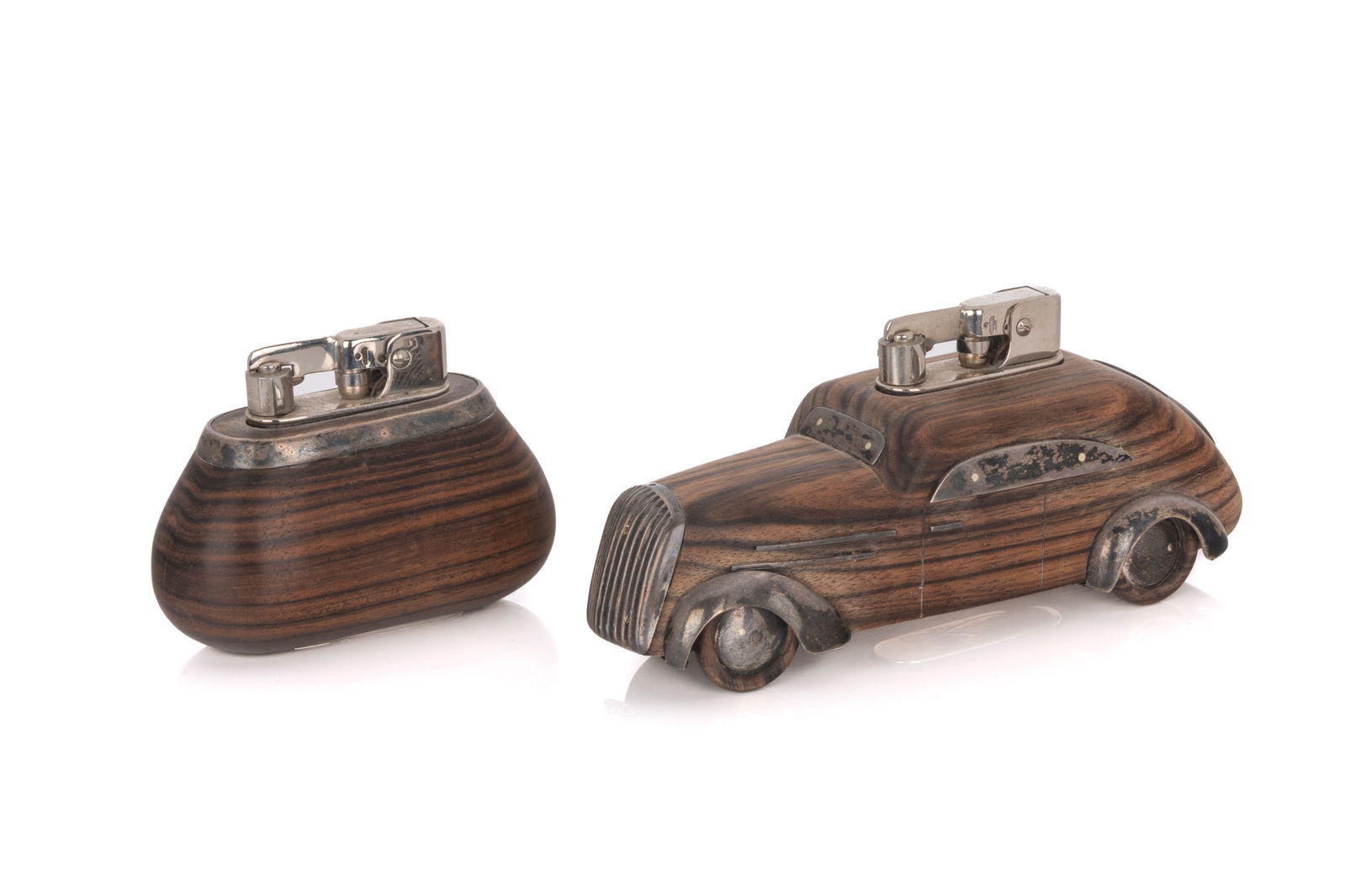 TWO NOVELTY SILVER MOUNTED LIGHTERS: Exotic carved wood in the shape of a vintage car with silver mounts by Lunder. Length of car 15cm (6in)
