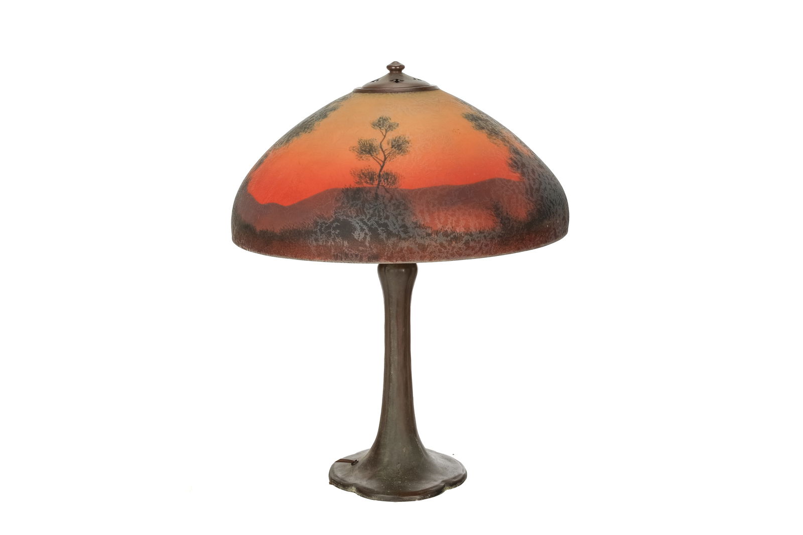 HANDEL REVERSE PAINTED LANDSCAPE TABLE LAMP: Landscape painted with trees and an orange sunset mounted to an Arts & Crafts bronze base, the shade signed Han 6957FU. Base unmarked. Dia. of shade: 45 cm (17 3/4 in.)