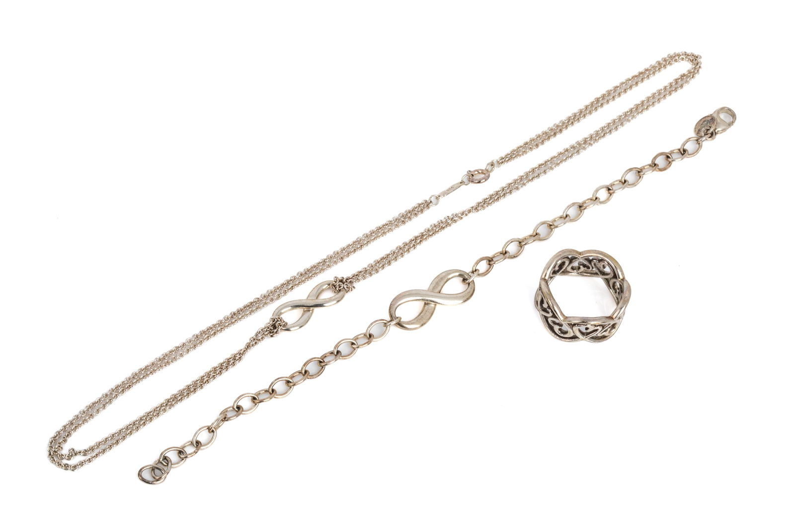 TIFFANY & Co. SILVER JEWELLERY TRIO 18.3g: Tiffany & Co. Paloma Picasso Loving Heart band ring in sterling silver, measuring 11mm wide. Size 7.25 5.9 gramsTiffany & Co. Infinity bracelet in sterling silver, 7.25 inches long. 6.3 grams