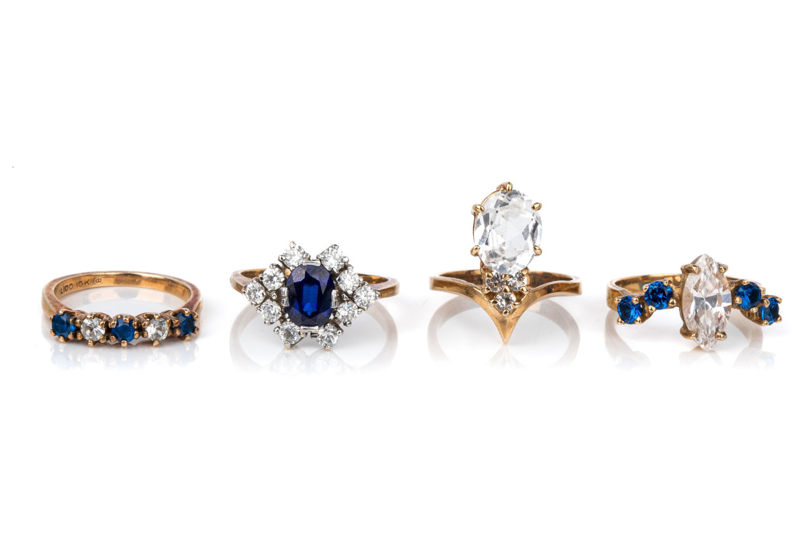 10K GOLD & IMITATION GEM RINGS 14.8g: 10K yellow gold cubic zirconia chevron ring measuring 19.5mm long by 7.8mm tall. Size 6 4.4 grams10K yellow and white gold cubic zirconia and imitation sapphire cluster ring measuring 12.8mm long by 5