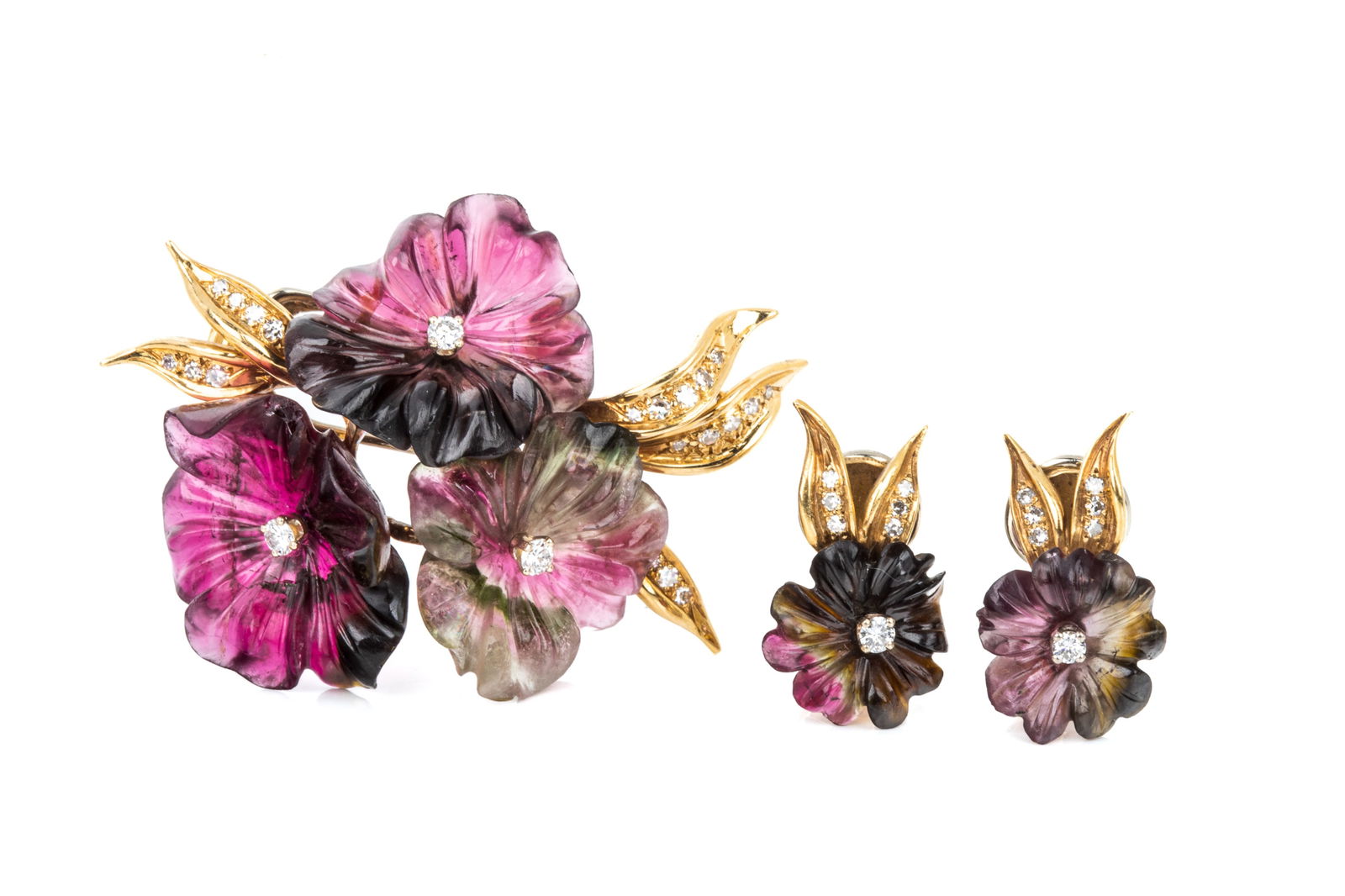 18K CARVED TOURMALINE BROOCH & EARRING SET 22.6g: 18K yellow and white gold brooch and clip on earring set. Brooch measures 46.9mm by 34.3mm, equipped with yellow gold hinge and trombone clasp, white gold double pin. Featuring 3 delicate carved parti