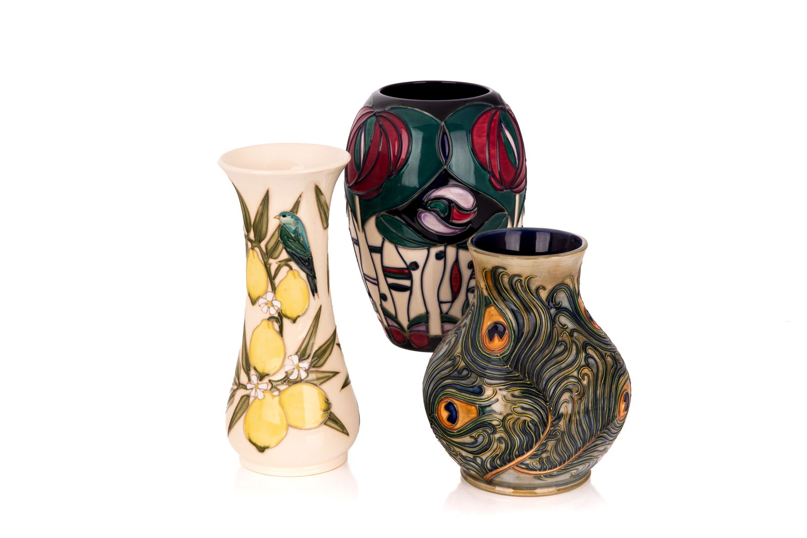 THREE MODERN MOORCROFT VASES: One flared vase with cream background featuring lemon plant and bird motif. One bulbous vase with pale green background and dimensional peacock feather motif. One wide-mouth polychromed vase with
