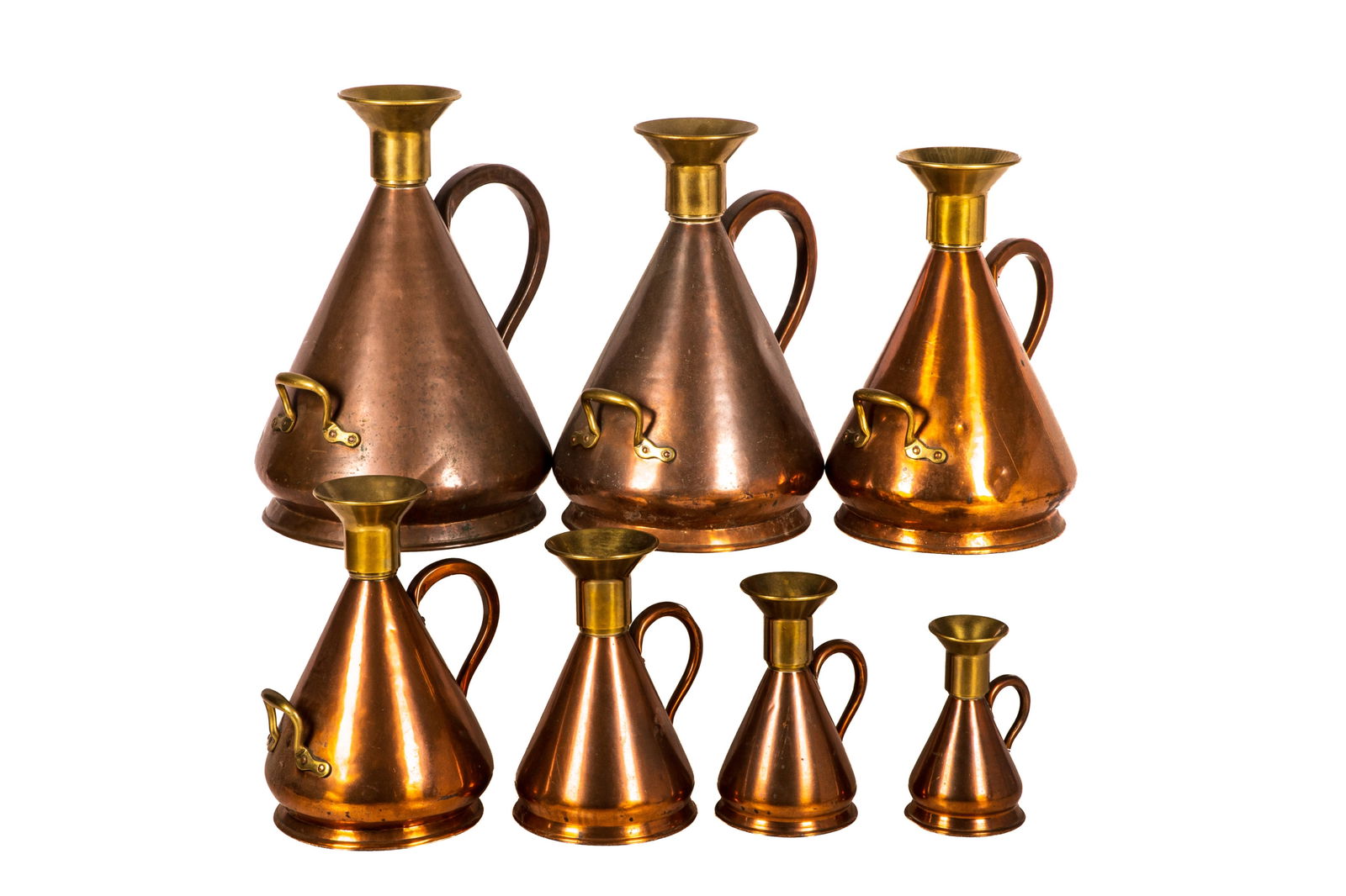 SEVEN ANTIQUE COPPER GRADUATED MEASURES: Jug form in copper with brass handles and spouts, probably English, 19th C. Largest H. 23" x Dia. 15" Smallest H. 9 3/4" x Dia. 5 7/8"