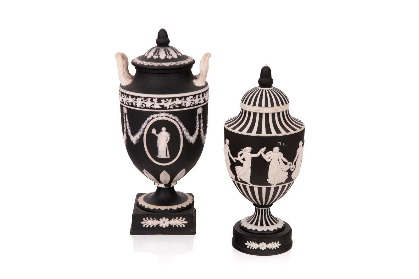 TWO WEDGWOOD JASPERWARE COVERED URNS: Both black ground with applied white jasper. Neo-Classical motifs. Vase model 40 and model 1202. Both with impressed marks to base. English, 20th c. Model 40 H. 30cm (11 3/4in) Model 1202 H. 26.5 (10