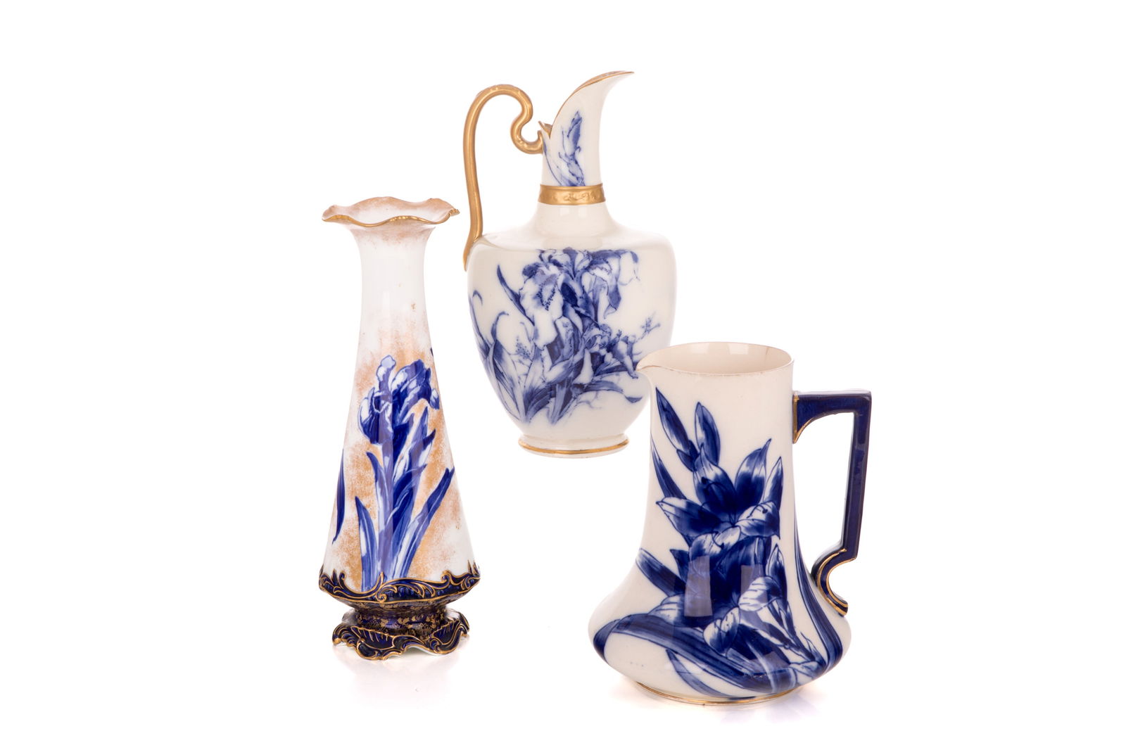 THREE DOULTON BURSLEM BLUE IRIS PATTERN VASES: The lot includes two ewers and a vase all with cobalt painted flowers and gilded accents. Vase H. 29.1cm x Dia. 10.4cm (11 1/2in x 4 1/8in) Pitcher H. 20.6cm x Dia. 16.7cm (8 1/8in x 6 5/8in)