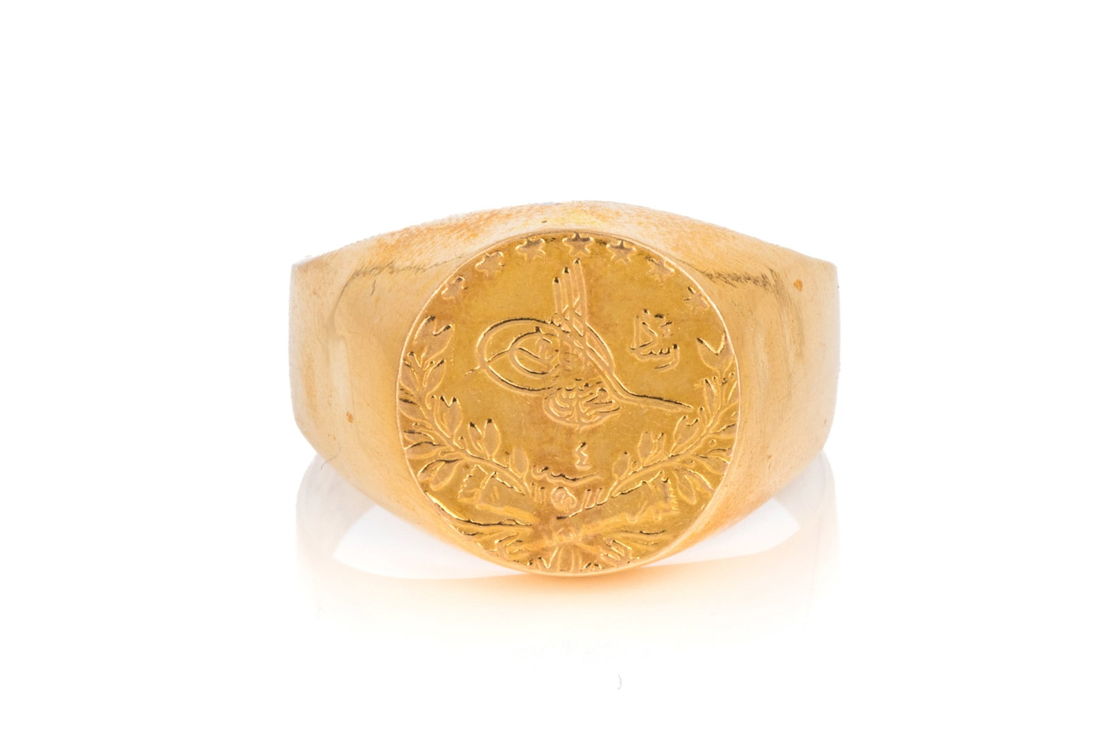 18K YELLOW GOLD SIGNET RING 6.5g: Yellow gold signet ring testing approximately 18K, decorated with a raised design to mimic a 25 Kurush coin. Measuring 15mm wide by 3.9mm tall.Size 12.25 6.5 grams