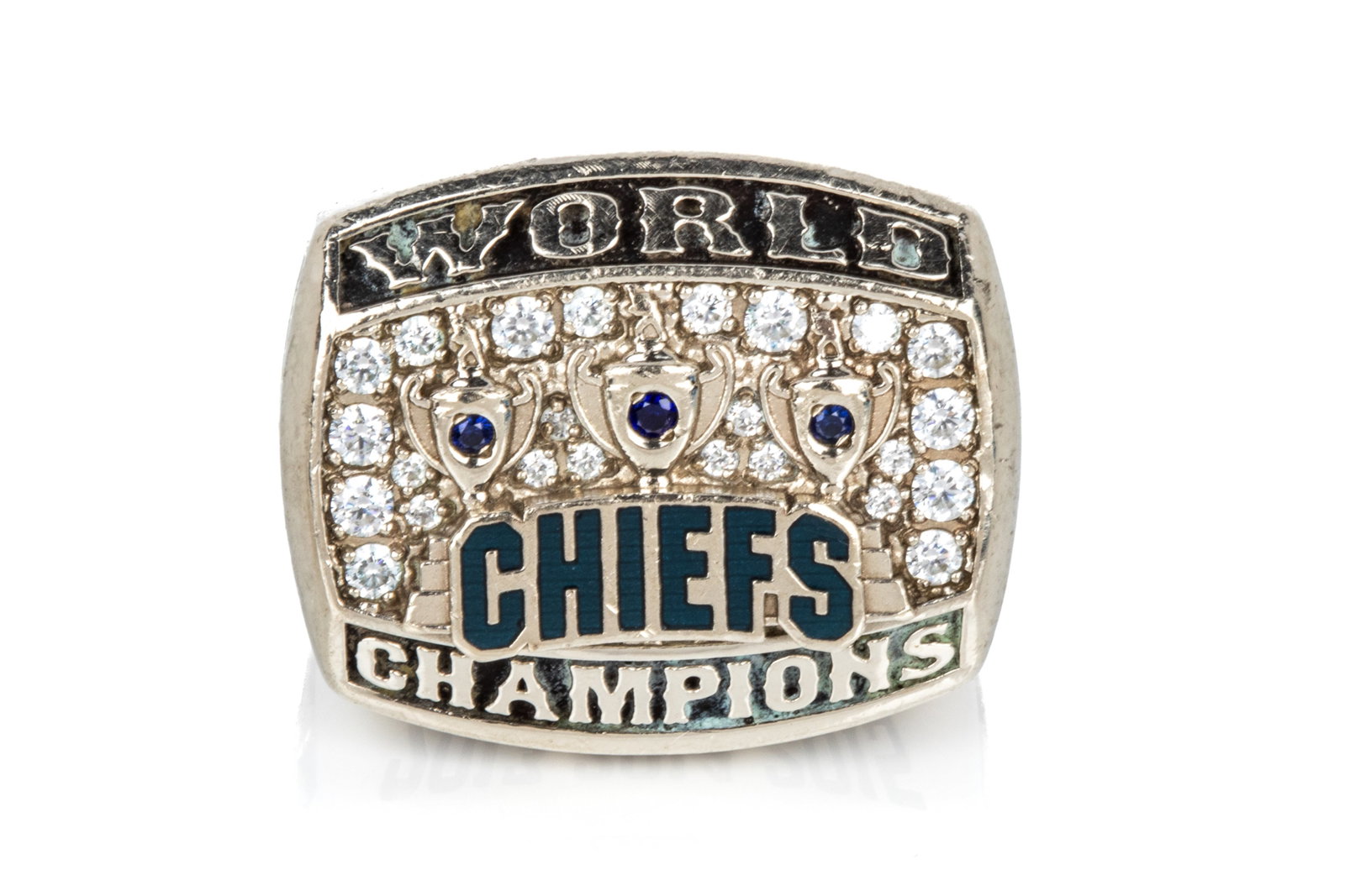 10K HILL UNITED CHIEFS CHAMPIONSHIP RING 52.5g: Custom made by Baron Championship Rings 10K white gold Hill United Chiefs championship ring measuring 25.3mm long by 9.2mm tall. Featuring cubic zirconia, blue enamel, andblackening patina. Size 11 52