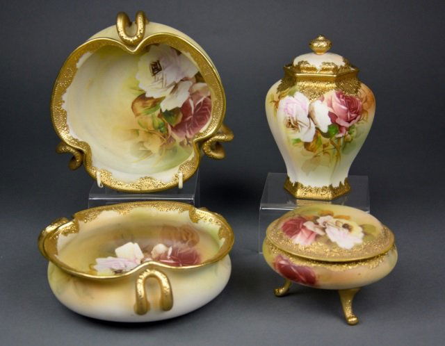 Four Nippon hand painted porcelain: - Lot comprised of blue leaf footed dresser jar (H: 3 1/8 in.), green leaf covered caddy (H: 6 1/4 in.), with two porcelain bowls with blue maple leaf mark D: 7 in. H: 2 1/1 in. Each with floral desig