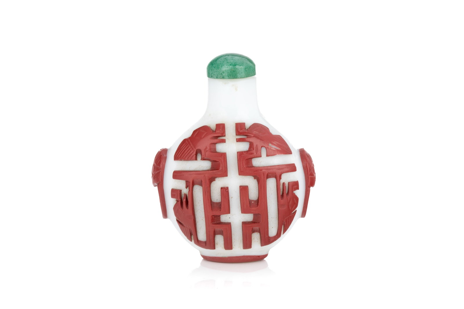 CINNABAR RED OVERLAY WHITE GLASS SNUFF BOTTLE: Of flattened ovoid form. Carved in a cinnabar red overlay to the opaque white ground, depicting archaistic kuilong motifs on both sides. Jadeite stopper. Qing dynasty, c. 1800. H. 6.5 cm Snuff Bottle 