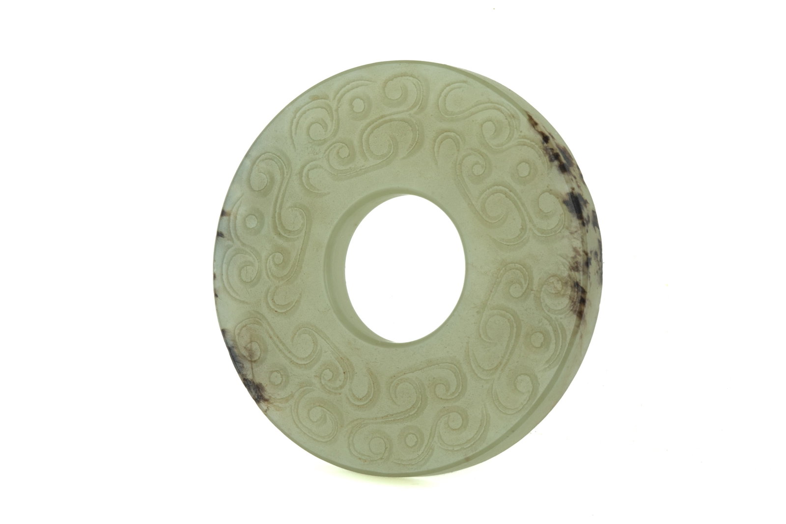 ARCHAISTIC PALE CELADON JADE BI DISC PENDANT: The stone with natural greyish inclusions. Both sides carved with archaistic scrolls. Diam. 4.8 cm