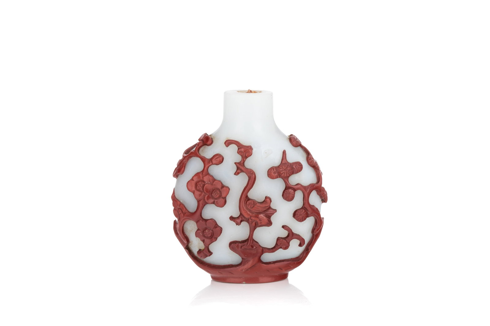 CINNABAR RED OVERLAY WHITE GLASS SNUFF BOTTLE: Of flattened ovoid form. Carved in cinnabar red overlay to a white ground, with a crane and plum blossoms on one side, and a deer and pine trees on the other. Qing dynasty, 18th century. H. 5.5 cm Snu
