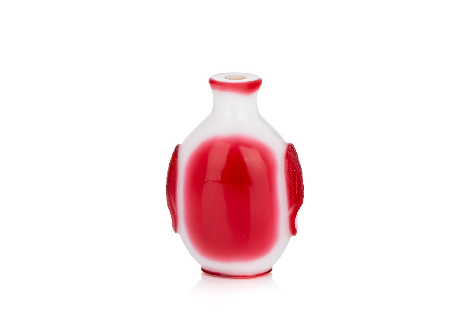 RED OVERLAY WHITE GLASS SNUFF BOTTLE: Of flattened oval form. Carved in a rosy ruby red overlay to a milky white ground. Two narrow sides with carved mythical beast handles. H. 6 cm Snuff Bottle Collection of John Mckeggie Rogers (1905-19