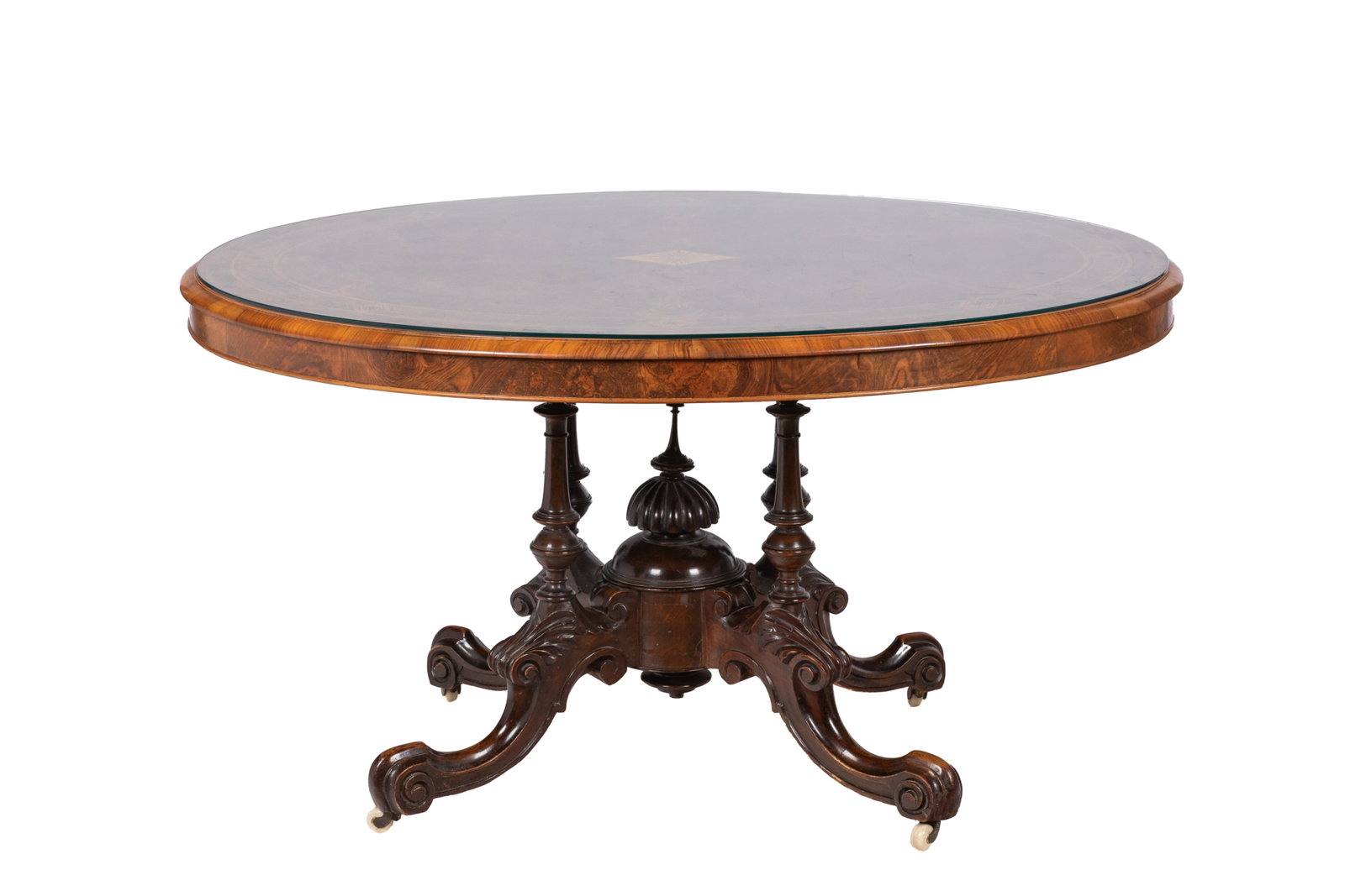 19th C ENGLISH BURLED WOOD BREAKFAST TABLE: Burled wood top showing distinct grain details accented in inlay border and lozenge centre, carved revival base on casters. H 29in x W 53in x D 40in