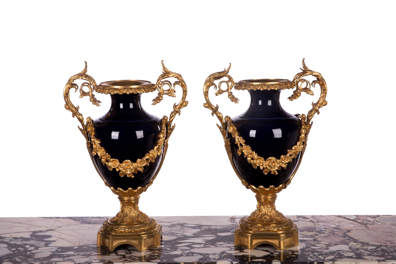 FRENCH BRONZE MOUNTED COBALT PORCELAIN URNS: Cobalt porcelain vases with ormolu mount, foliate handles and draping floral swags on squared bases, possibly Sevres, French late 19th C. H 13 1/2in