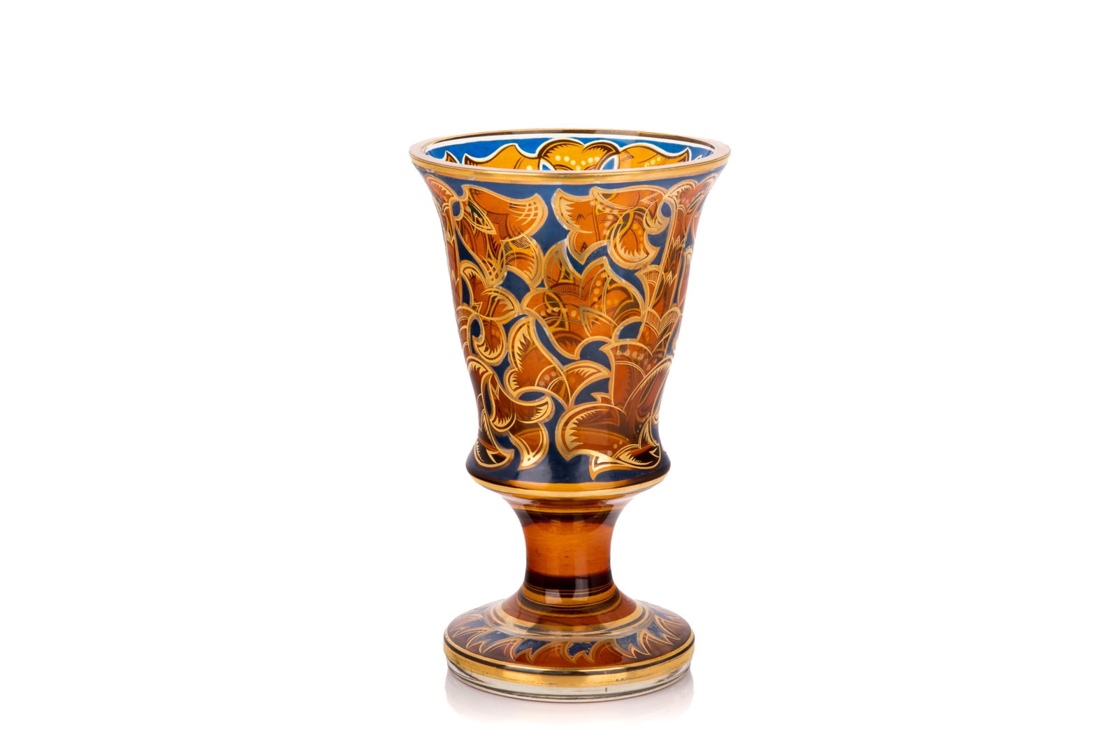 BOHEMIAN ART NOUVEAU GOBLET: Amber glass with a cobalt blue casing overlay. Flared trumpet-shaped body resting on a short pedestal base with gold gilt styling. Intricate, stylized floral scrollwork serves as the dominant