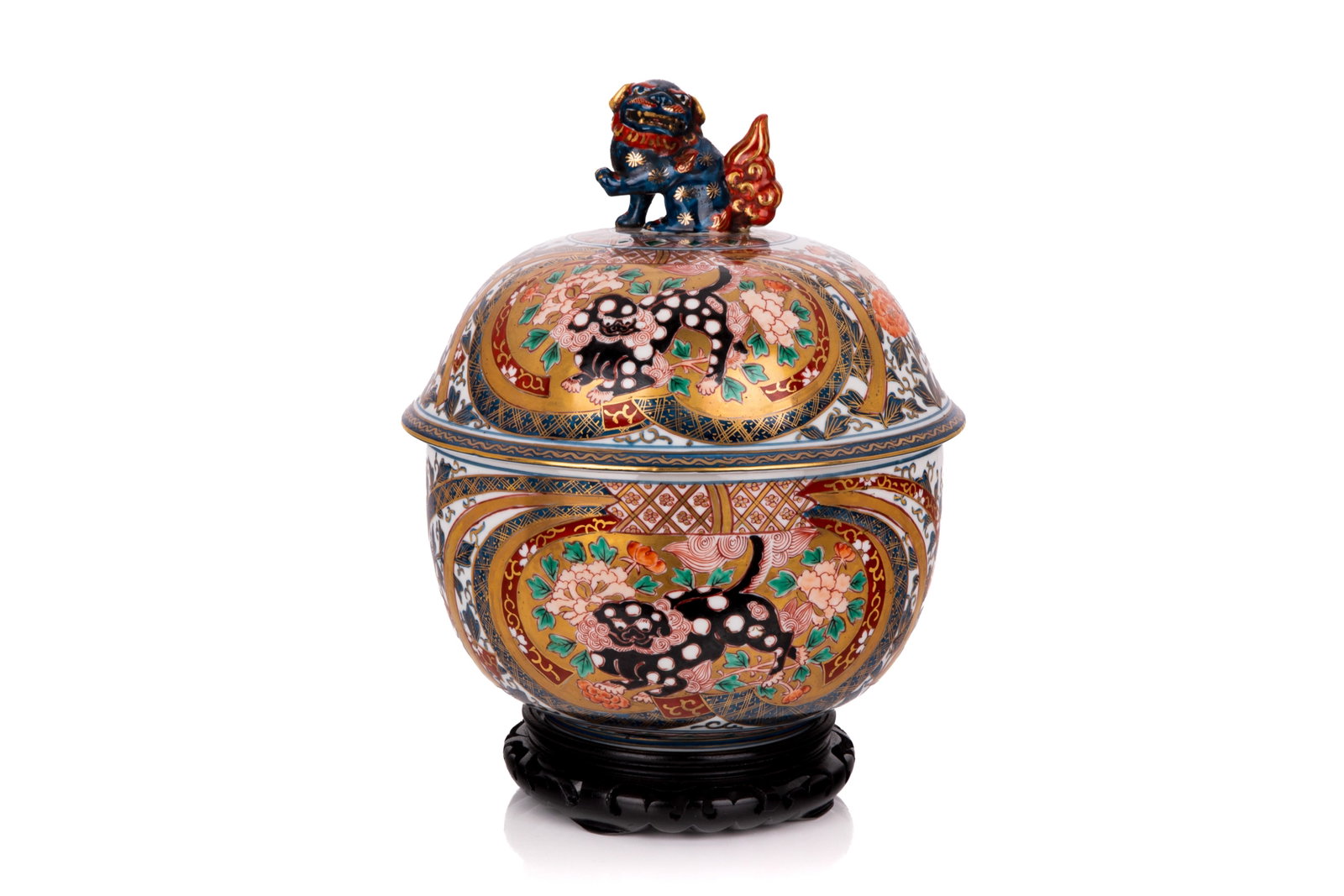 JAPANESE IMARI PORCELAIN COVERED JAR: A vibrant Imari porcelain covered jar featuring an overall round silhouette, decorated in traditional underglaze blue, iron red, and gilt polychrome enamels. The high-domed lid is surmounted by a
