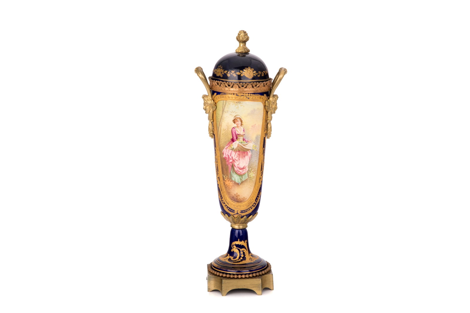 FRENCH PORCELAIN COVERED URN: A French Sevres style mounted porcelain covered urn, late 19th to early 20th century. Depicting a maiden carrying a basket of flowers, grotesque bronze mounts. H. 11 7/8in (30.3cm)