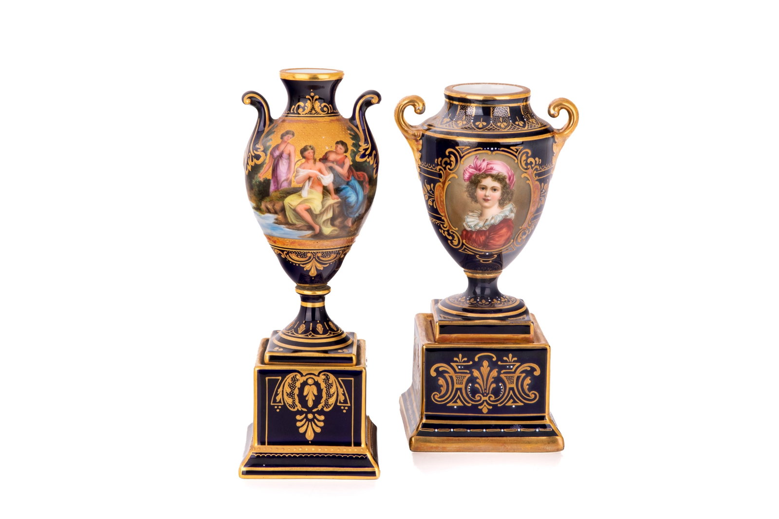 TWO VIENNA COBALT BLUE PORCELAIN URNS: One finely painted of the three graces on a gilded landscape titled Ninfas Bailando, the second with white enamel jewelling titled Palais Royal Louise Lebrun, beehive marks to underside of squared bas