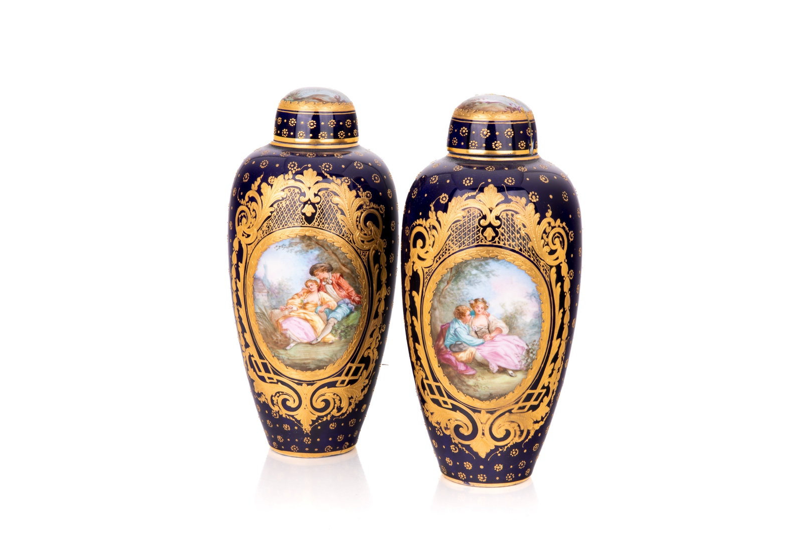PAIR OF FRENCH PORCELAIN COVERED URNS: A pair of French S?vres style porcelain covered urns, late 19th to early 20th century. Both painted with Rococo-style pastoral scenes depicting courting couples in romantic landscapes. H. 9 1/2in (24.