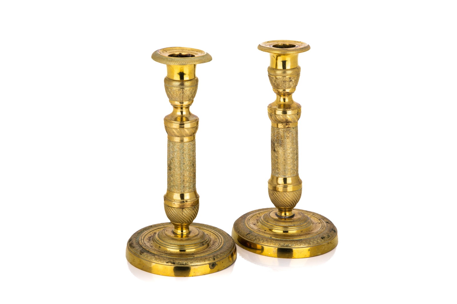 A PAIR OF FRENCH EMPIRE BRASS CANDLESTICKS: A pair of French Empire brass candlesticks, each designed with a turned and tapered columnar stem over a stepped circular base. H. 8in (20.3 cm)
