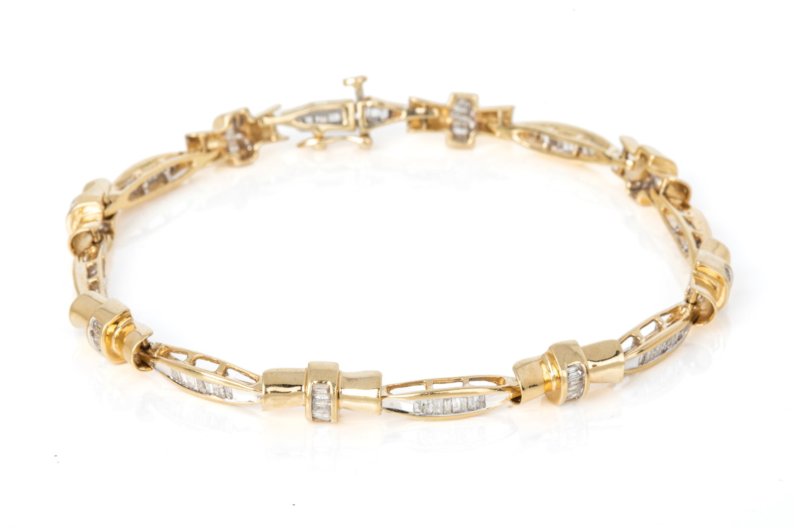 14K GOLD & DIAMOND TENNIS BRACELET 9.3g: 14K yellow gold tennis bracelet measuring 7 inches wearable length by 5.7mm wide, equipped with a hidden plunger clasp and side safety. Featuring 104 tapered baguette cut diamonds of I2-JK quality. 9.