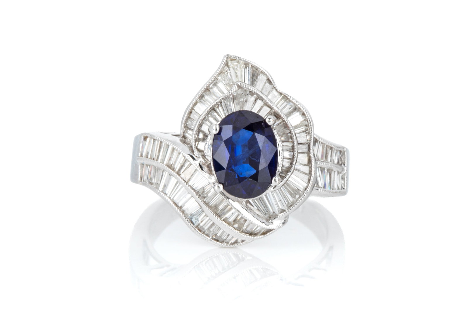 14K GOLD SAPPHIRE & DIAMOND RING 4.7g: Rhodium plated yellow gold ring testing approximately 14K measuring 17.2mm long by 7.9mm tall. Featuring 1 oval mixed cut medium blue sapphire accented by tapered baguette cut diamonds. Size 5.75 4.7 