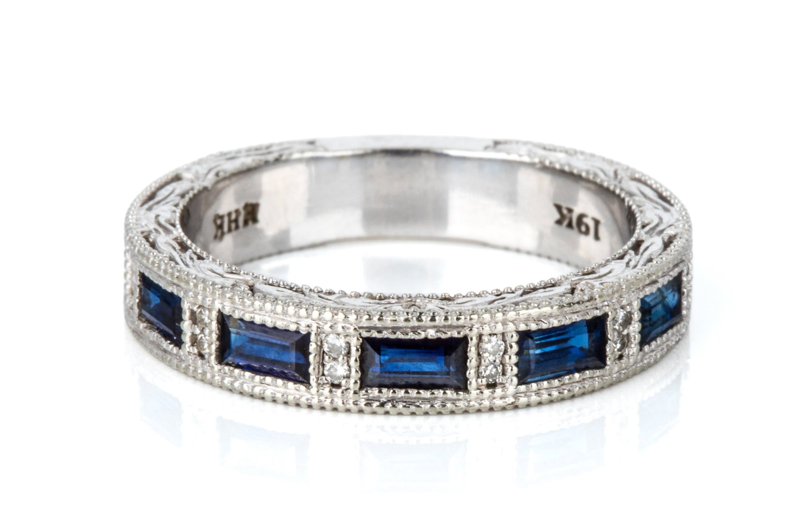 19K SAPPHIRE & DIAMOND ORNATE BAND 6.4g: 19K white gold ornate band ring measuring 4.2mm wide by 2.3mm thick. Featuring natural blue sapphires and petite round brilliant cut diamonds. Size 7.75 6.4 grams