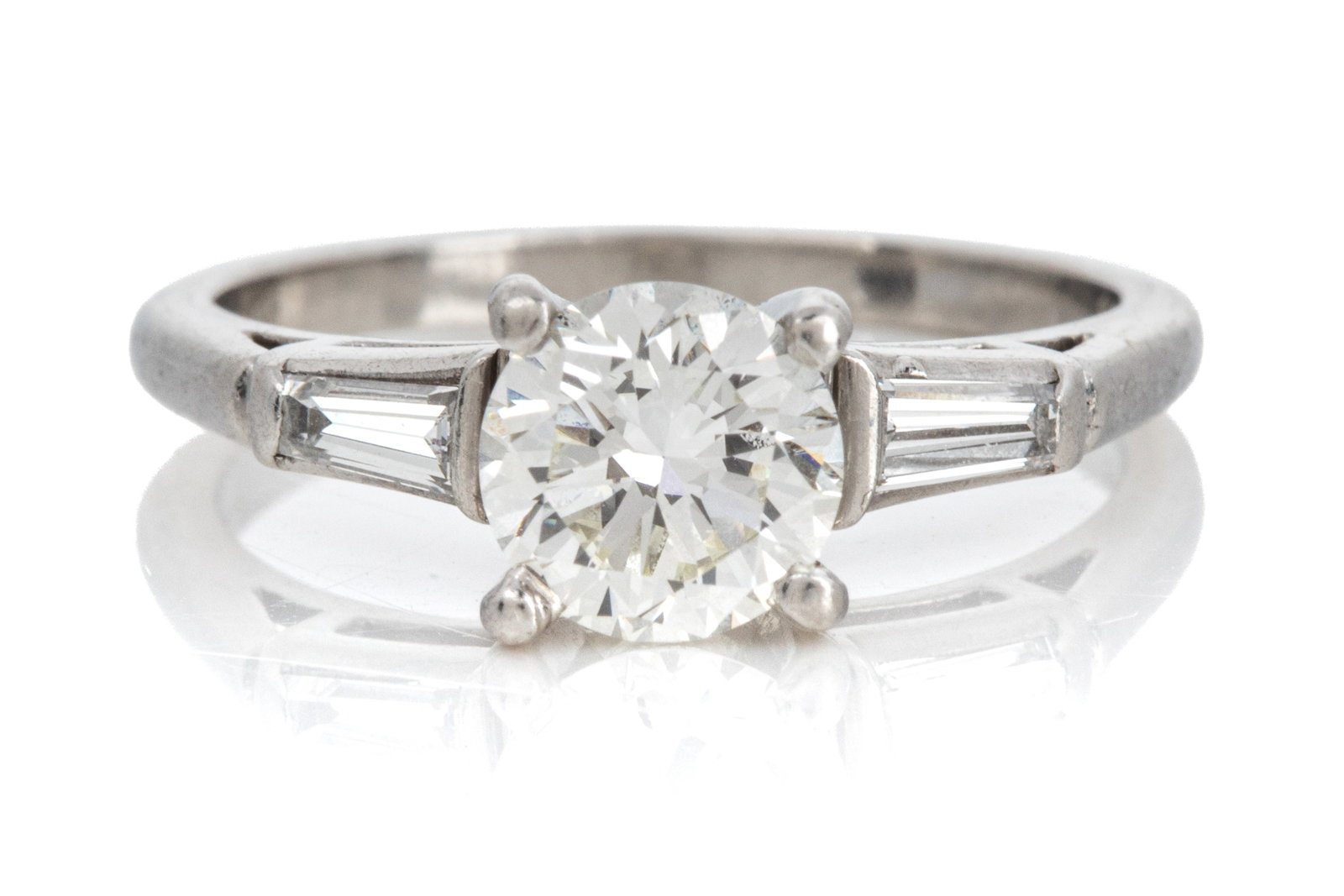 PLAT 1.01ct VS2-JK DIAMOND RING 4.5g: Platinum diamond ring measuring 2.7mm wide at shoulders, by 7.7mm tall. Featuring 1 round brilliant cut diamond weighing approximately 1.01ct of VS2-JK quality. Accented by 2 tapered baguette cut