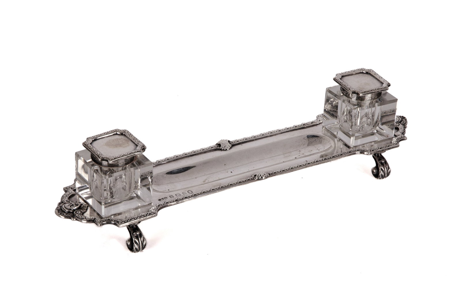 LONG BIRMINGHAM JUBILEE SILVER INKSTAND, 203g: Elongated form on acanthus feet fitted with two glass ink bottles (one chipped), Robinson & Co. Birmingham, 1934 203g, not inclusive of silver lids to glass inkwells. Inkwell H. 1 1/2in (3.6cm)