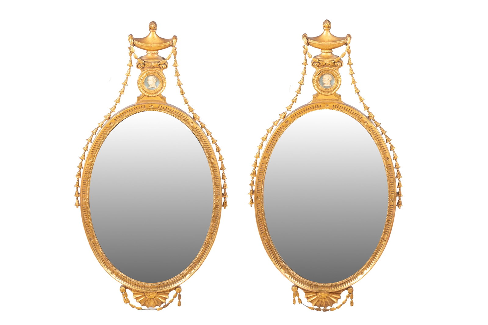 PAIR OF ADAMS-STYLE GILTWOOD MIRRORS: Oval gilt wood framed with Wedgwood type portrait profiles, Adam's urn finials. 19th / 20th C. H 41" x L 20"