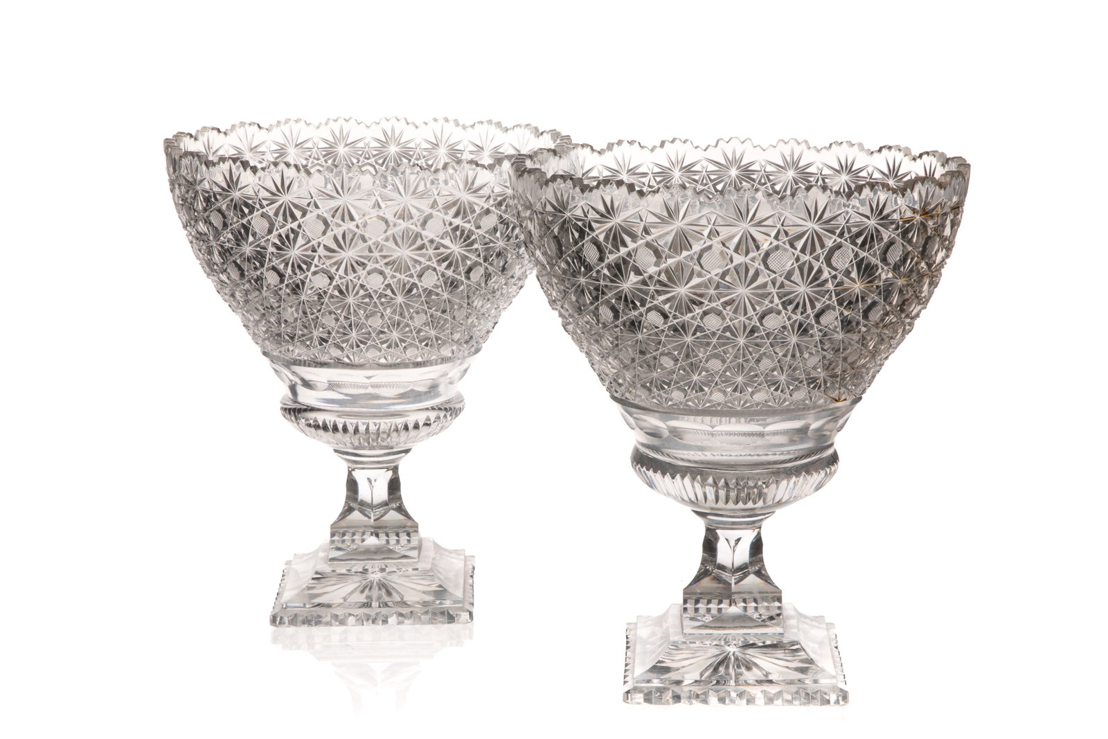 PAIR OF CUT GLASS FOOTED PUNCH BOWL: "Stars and Buttons" pattern. The bowl features an intricate, deep-cut crystal design with a scalloped edge and a footed, square base. H. 11in x W. 9 1/2in (28cm x 24.5cm)