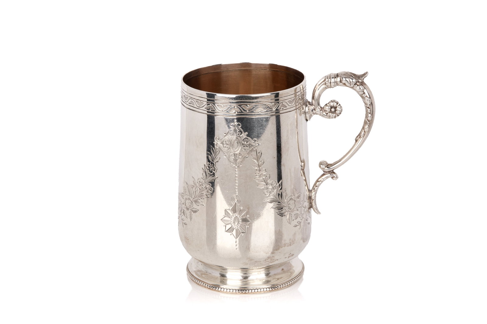 VICTORIAN SILVER ENGRAVED MUG, 153g: The body is decorated with floral garlands, fitted with a scrolled handle, gilt interior. Hallmarked for Sheffield, 1885, maker John Round & Son Ltd. Weight 153grams H. 4 1/4in (10.8cm)