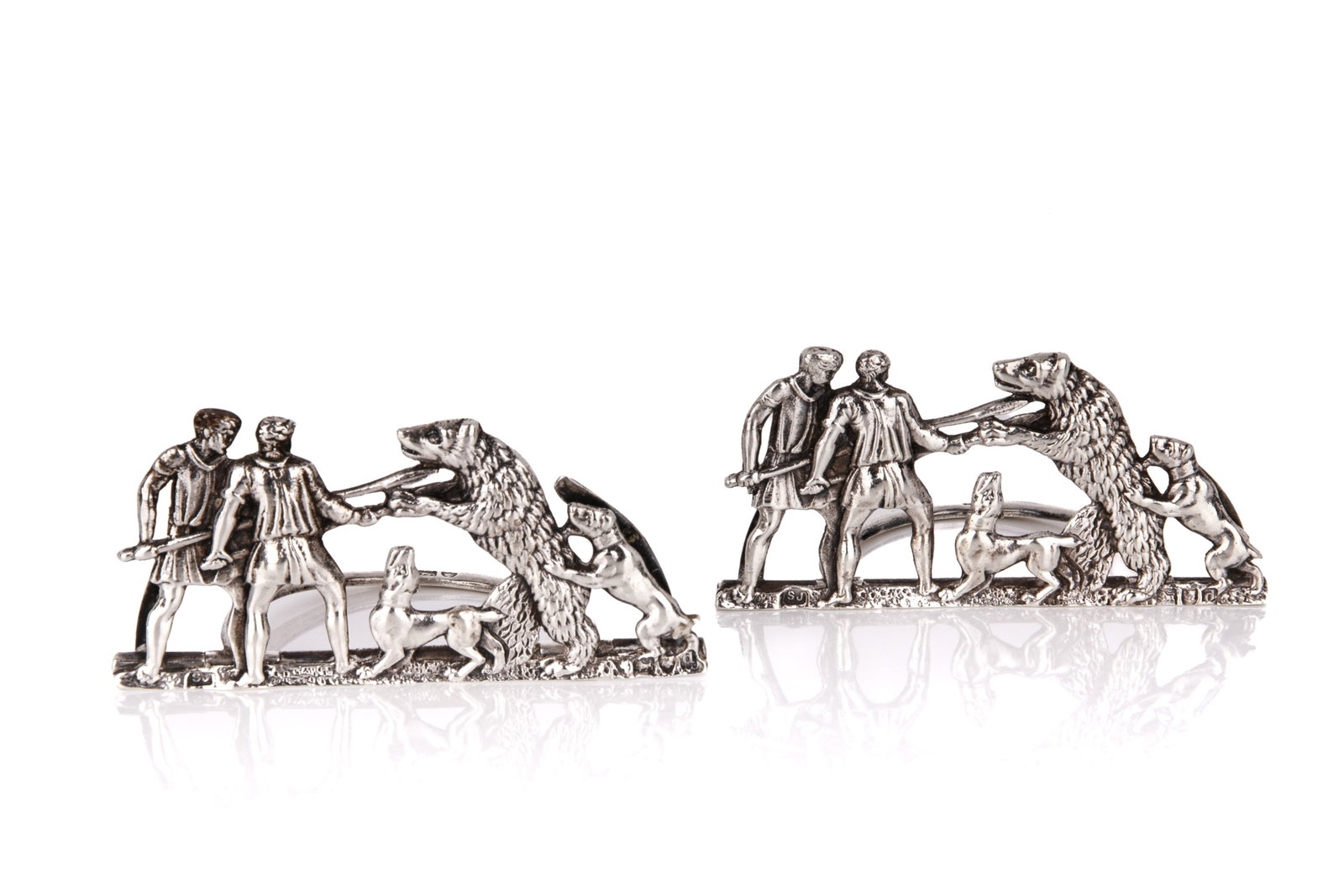 TWO LATE VICTORIAN SILVER MENU HOLDERS , 51g: With cast bear hunt figural motif, Samuel Jacob, London, 1899 .H. 1 1/4in x L. 2 3/4in (3.2cm x 6.9cm)