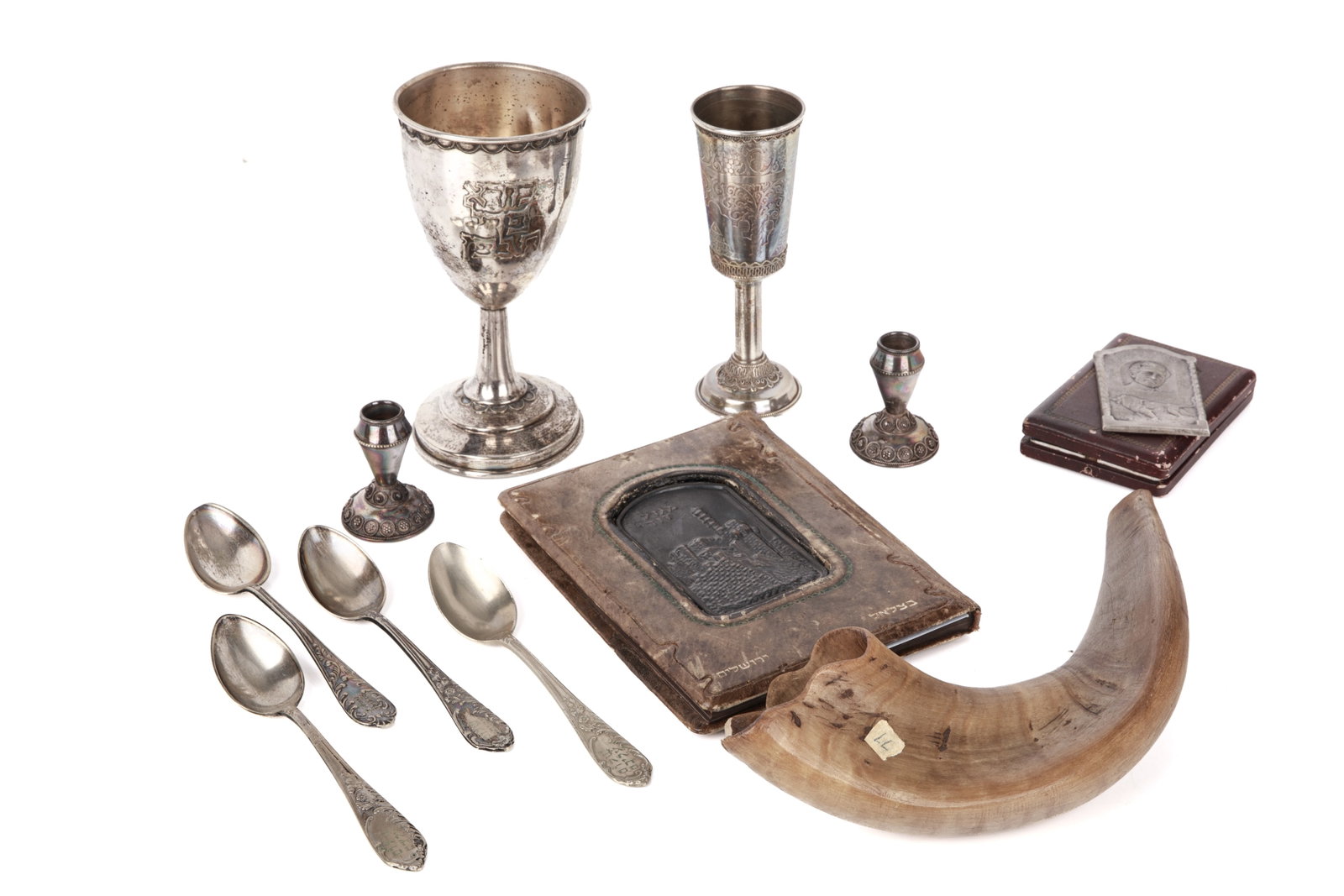 GROUP OF JUDAICA OBJECTS: Including two Israeli silver kiddush cups, small filigree travel candlesticks, silvered bronze plaque in memoray of Joseph Trumpeldor by Bezalel School, a Bezalel School leatherbound Hebrew book and