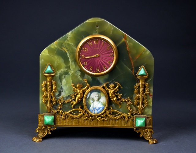 Austrian 8 day green onyx & gilt ormolu clock: red enamel dial- signed Schild & Co. at reverse. Front decorated with gilt putti figures flanking Victorian cartouche. 7 3/8 x 7 1/2 x 2 1/2 in.